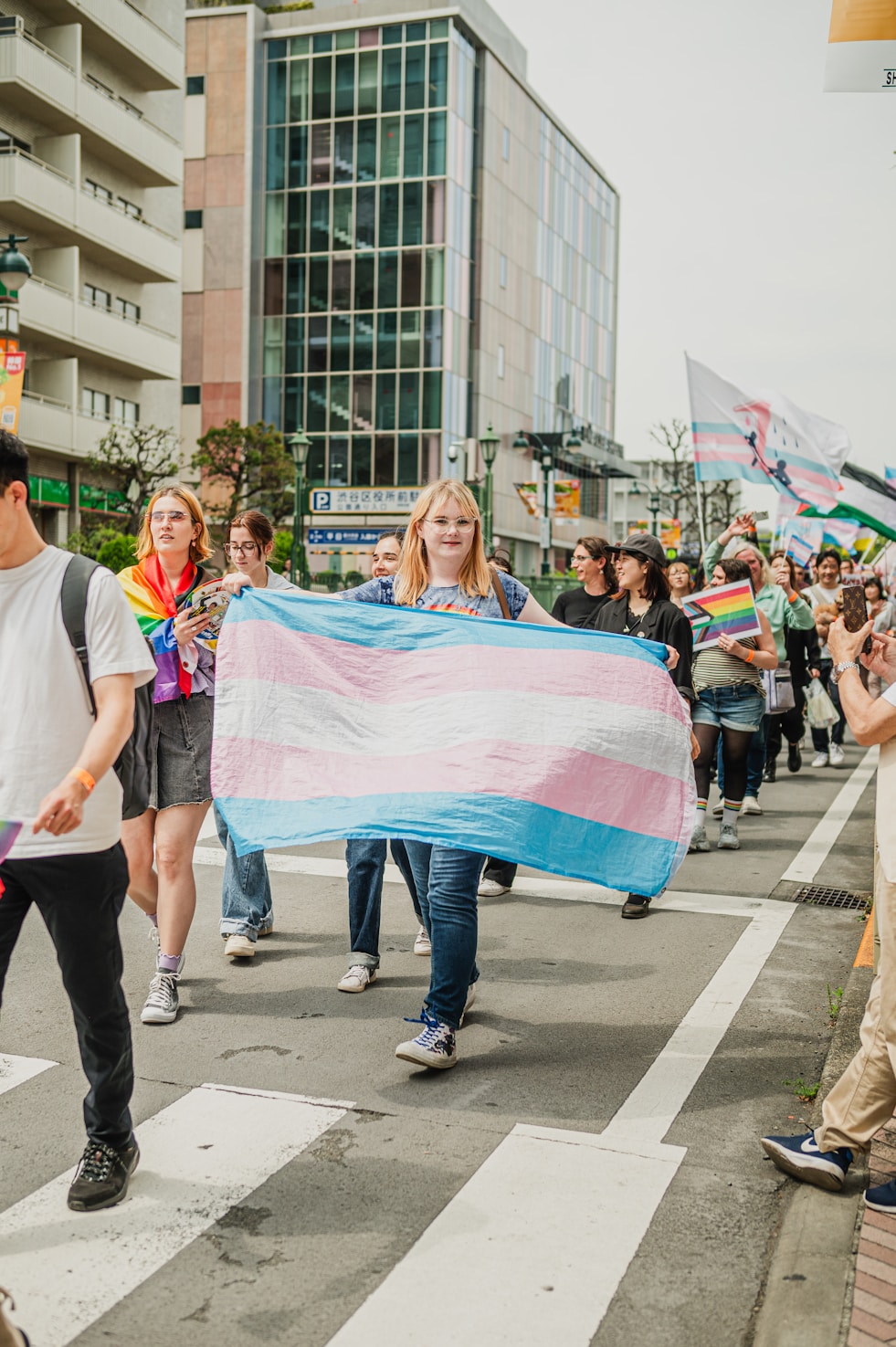 Person displaying a large trans pride flag at a march
